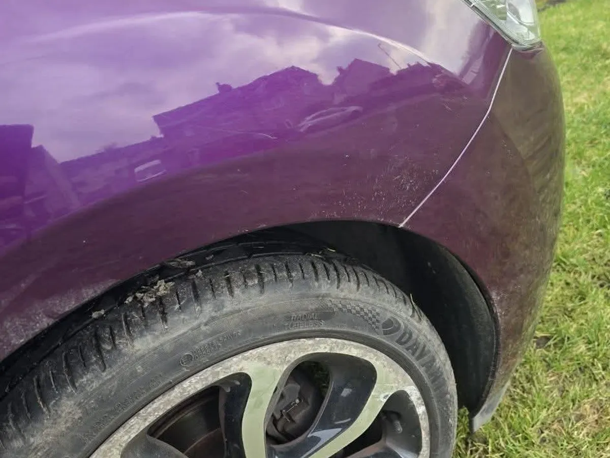 The same purple front wing after repair, the reflection of the houses opposite running unbroken across it.